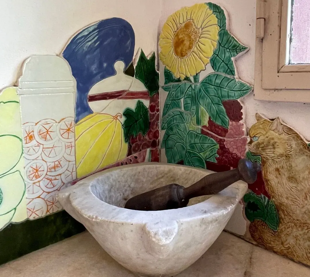 Marble mortar in front of a hand-painted ceramic wall with sunflower and cat